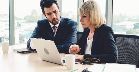 Man en vrouw achter laptop op een kantoor in bespreking