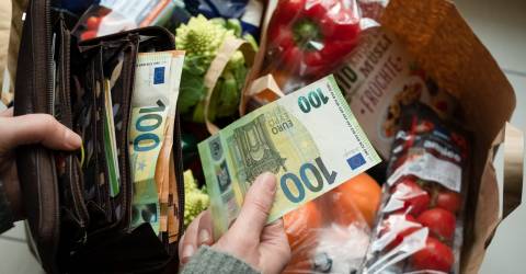 Een tas vol boodschappen met op de voorgrond een portemonnee met briefgeld